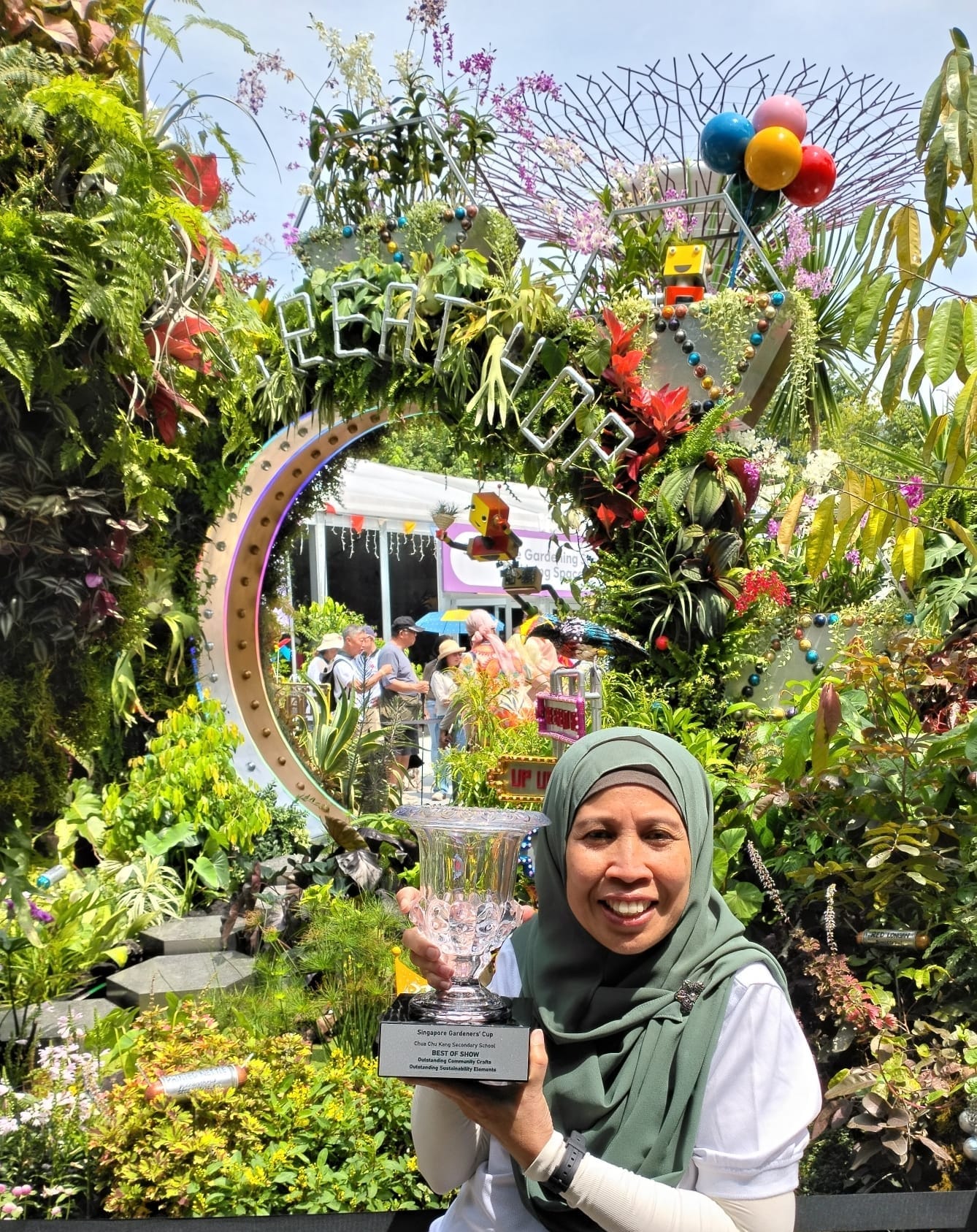 CCKSS teacher proudly displays the Best of Show trophy beside the award-winning garden.